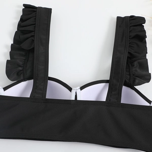 Detail shot of black bikini top featuring elegant ruffle straps and fine textured fabric