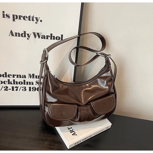 Detail of dark brown glossy patent leather hobo bag with front pockets and silver hardware