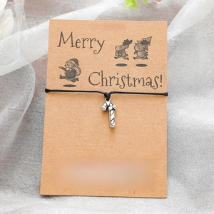 Close-up of a Christmas candy cane charm bracelet on a festive kraft wish card