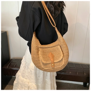 Detail of straw woven shoulder bag with brown leather flap pocket and long strap