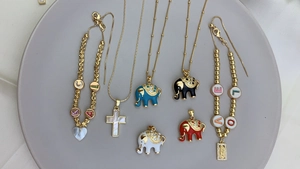 Flat lay of gold plated necklaces and bracelets with colorful enamel elephant charms