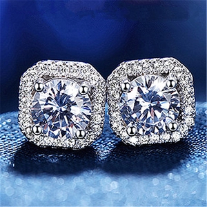 Macro shot of silver halo stud earrings with round cut center stone and pavé setting