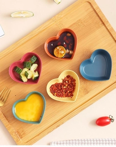 Colorful heart-shaped wheat straw seasoning dishes arranged on a wooden board