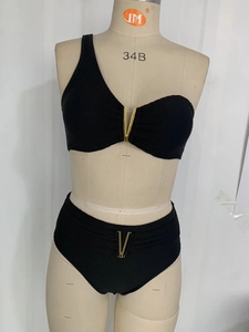 Gros plan du bikini noir côtelé avec détails de boucles métalliques dorées en V