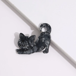 Detail of dark grey textured acrylic cat brooch with smooth finish on white background