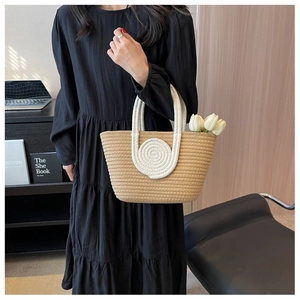 Detail of hand-woven cotton rope flowers and sturdy handles on a straw tote bag