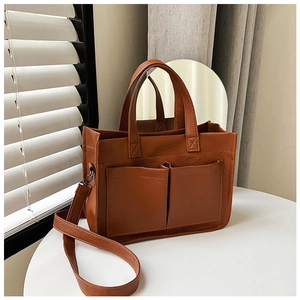 Detail of caramel faux leather tote bag with dual front pockets and adjustable strap