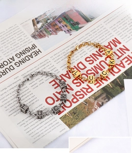 Detail of gold and silver chunky chain bracelets with Lucky letter square beads