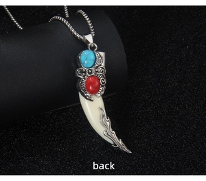 Close-up of wolf tooth pendant back featuring dragon detail and inlaid gemstones