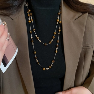 Detail of layered vintage tiger eye bead necklace on a stylish brown suit blazer