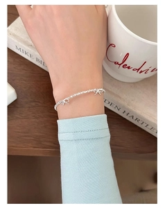 Dettaglio del bracciale con fiocco in argento s925 al polso su uno sfondo di stile elegante