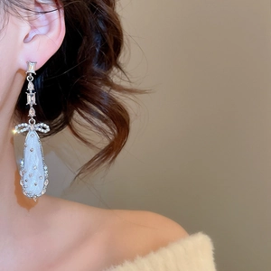 Close-up of elegant silver bow drop earrings with sparkling rhinestones on model