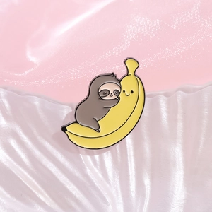 Cute cartoon sloth hugging a smiling yellow banana enamel pin on shell texture background