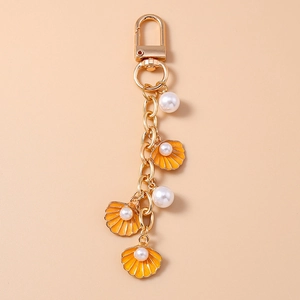 Detailed shot of golden keychain with orange shells and elegant white pearls decorations