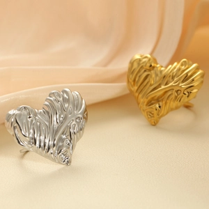 Detailed macro shot of gold and silver heart-shaped rings with wavy surface textures