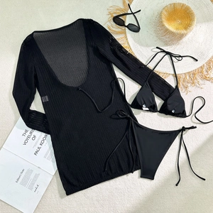 Flat lay of black three-piece bikini set with sheer mesh cover-up and beach accessories