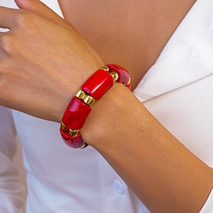 Close-up of geometric red acrylic blocks with gold metal spacers on a wide bracelet
