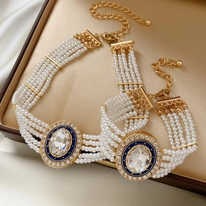 Close-up of multi-strand pearl jewelry set with blue crystal pendant in a gold-lined box