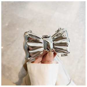 Close-up of a silver bow-shaped clutch bag with metallic finish and thin chain