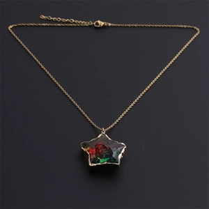 Macro detail of gold stainless steel chain with iridescent star pendant on black background