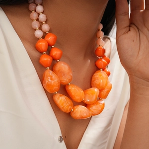 Detail of layered acrylic necklace with chunky orange marble beads and gold accents