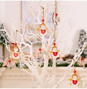 Detail of wooden angel and reindeer ornaments hanging on a white festive branch