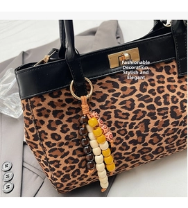 Dettaglio borsa scamosciata leopardata con chiusura dorata e nappa di perline