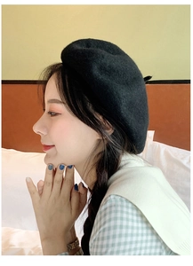 Side view of a minimalist black wool beret with soft felt texture on a model