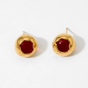 Detail view of round golden stud earrings with vibrant red enamel hollow sphere design