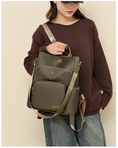 Detail of olive green oxford backpack with gold zippers shown on a model in profile