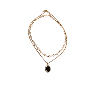 Vintage layered gold necklace with black oval pendant and heart link chain details