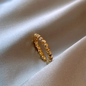 Dettaglio macro dell'anello a sfere placcato oro 14k con trama a cubi su seta