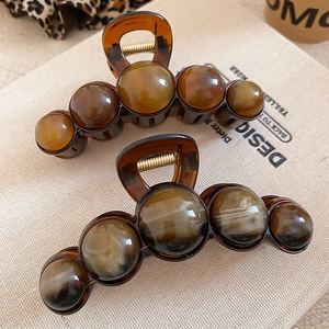 Detail of amber acrylic hair claws with smooth geometric design and strong spring