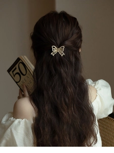 Detail of elegant gold butterfly hair clip with pearl embellishments in wavy brown hair