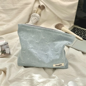 Detail of light blue denim makeup bag with bow patterns and Sozakka brand label
