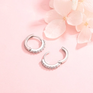 Elegant S925 sterling silver hoop earrings with zircon stones on a pink floral background