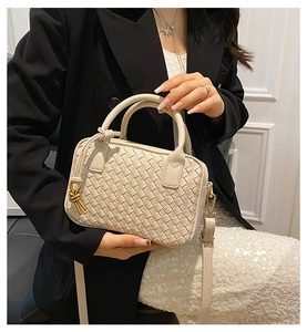 Detail of beige woven Boston handbag with gold metal hardware and detachable strap