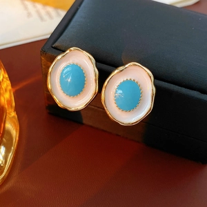 Detailed shot of vintage oval enamel earrings in gold and sky blue on a black box