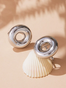 Macro detail of glossy silver hollow chunky hoop ring on a shell with elegant plant shadows