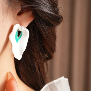Close-up of vintage enamel flower petal earring with pearl detail worn by a model