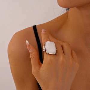 Close-up of a silver geometric ring with a white square stone on a model's finger