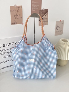 Detail of blue gingham tote bag with pink bow print and bright orange rope handles