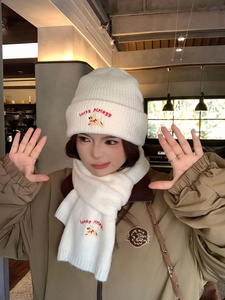 Detail of cream knit hat and scarf set with Lucky Piplegg embroidery and dog patch