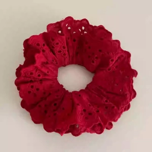 Détail d'un chouchou en dentelle rouge double couche avec motifs floraux ajourés complexes