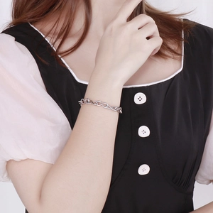 Gros plan d'un bracelet en acier inoxydable argenté avec maillons en huit au poignet