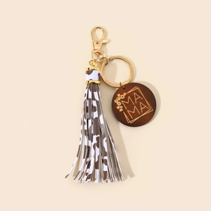 Detail of MAMA wooden charm with brown cow print tassel and gold lobster clasp