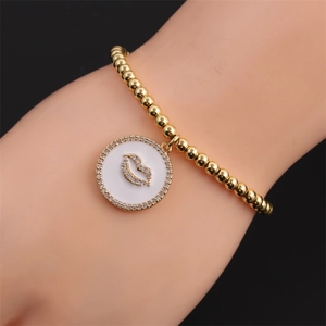 Bracciale a sfere dorate con ciondolo a labbra e smalto bianco da donna