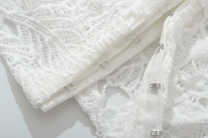 Detail of white floral lace fabric with adjustable metal hook-and-eye closures