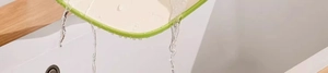 Close-up of beige antibacterial cutting board being rinsed under running water in a sink