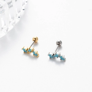 Close-up of curved cartilage studs with turquoise stones and secure ball back closures